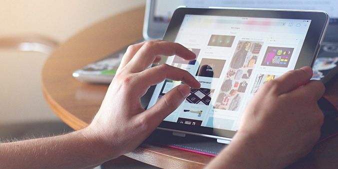 A person's hand using an ipad to look at images.
