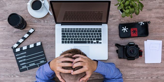 male holding head in front of a computer