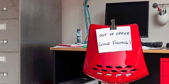 Empty chair in office with sign "Out office - Gone Fishing!"
